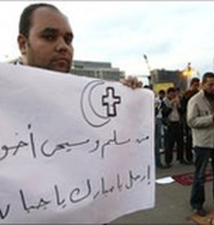 Un cristiano copto con un cartel que dice: “Musulmanes y cristianos somos hermanos, vete Mubarak, eres un cobarde”.