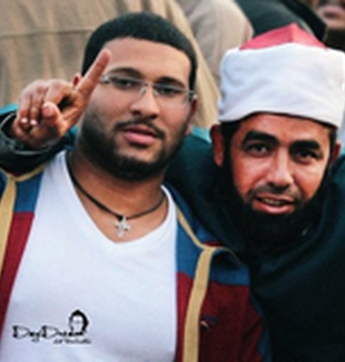 Un cristiano copto y un imán musulmán alzan los dedos con el signo de la victoria. 