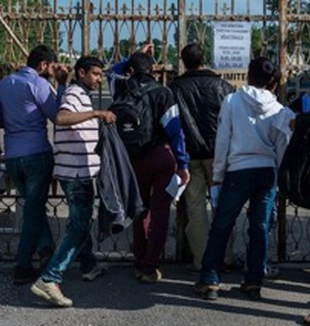 Un grupo de refugiados ante la verja.